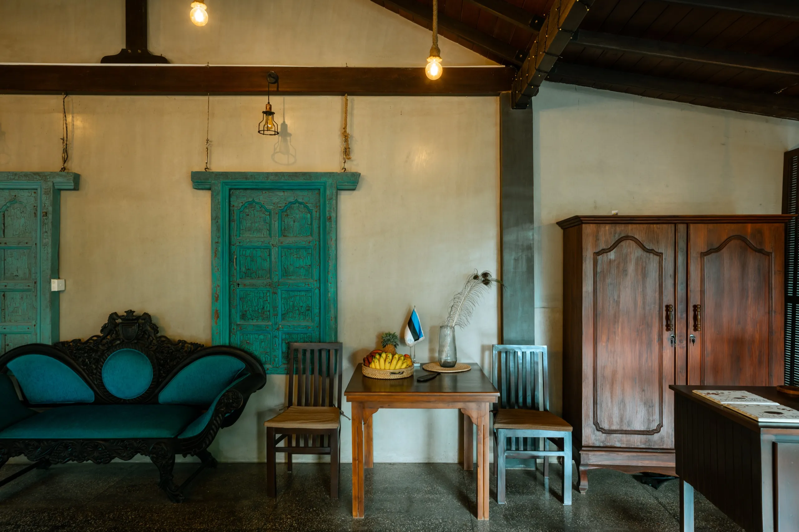 A corner of the restaurant floor: turquoise settee, a small table with a bowl of fruit and a dark timber cabinet
